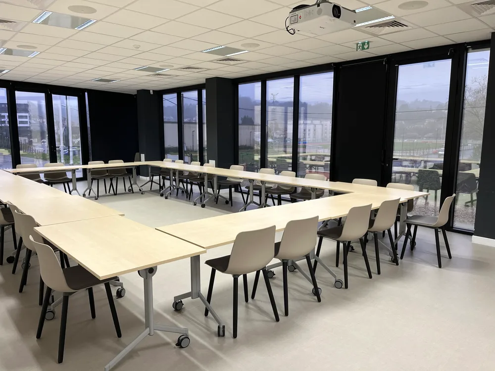 Grande salle modulable de l'espace Aliénor, tables en U et vue sur l'extérieur.