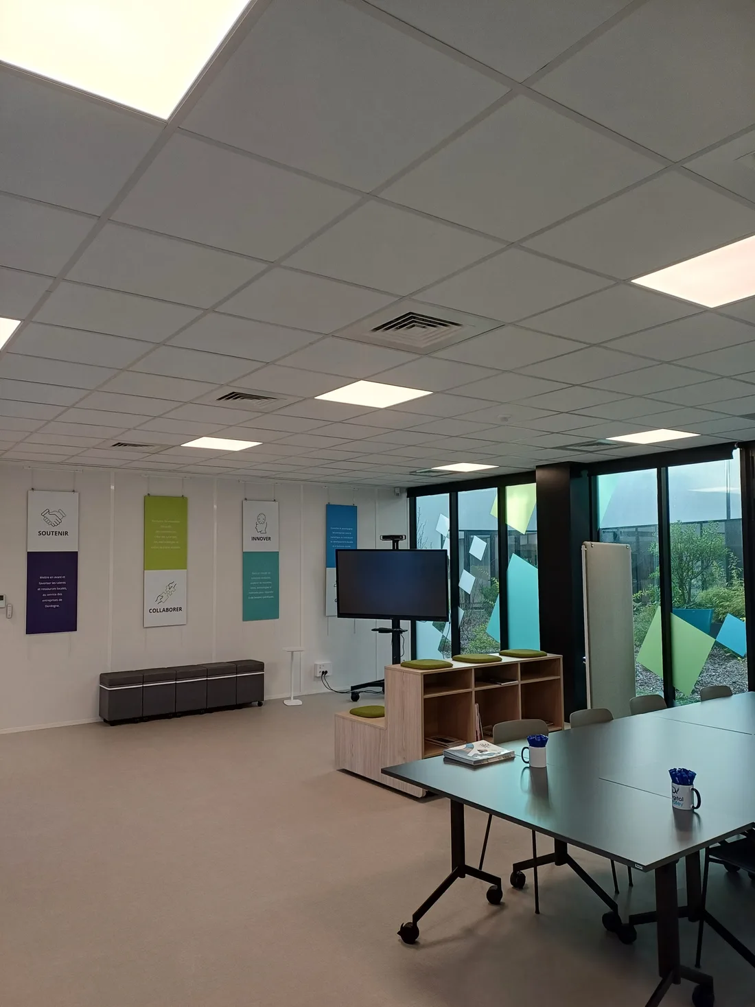 Salle de réunion et mur des valeurs de Digital Valley, avec écran et banquette.